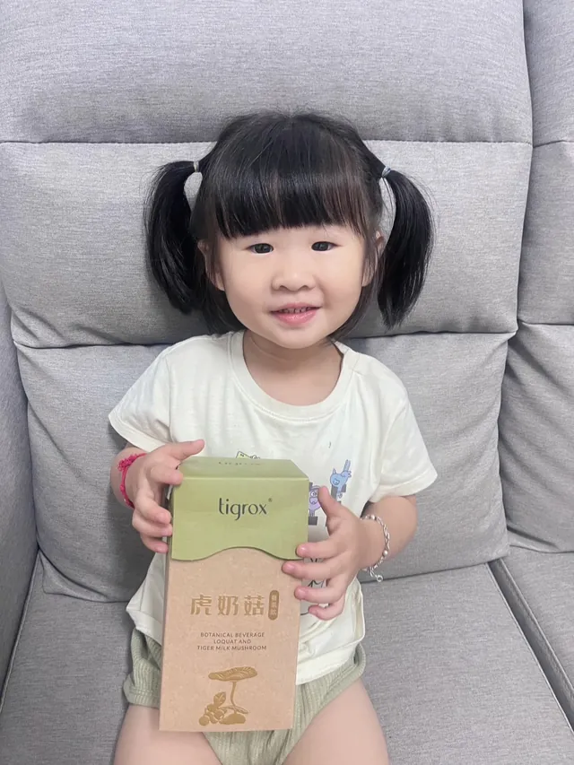 孩子坐在沙發上手持虎奶菇養氣飲外盒